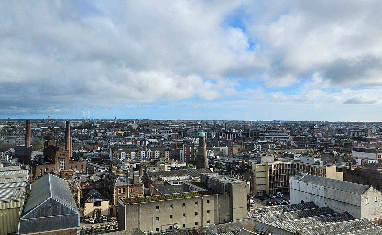 An aerial view of the Liberties, with the Roe & Co Distillery and the windmill visible, in front of a cloudy blue sky