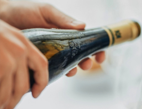 A person holding a German wine bottle pouring in a glass