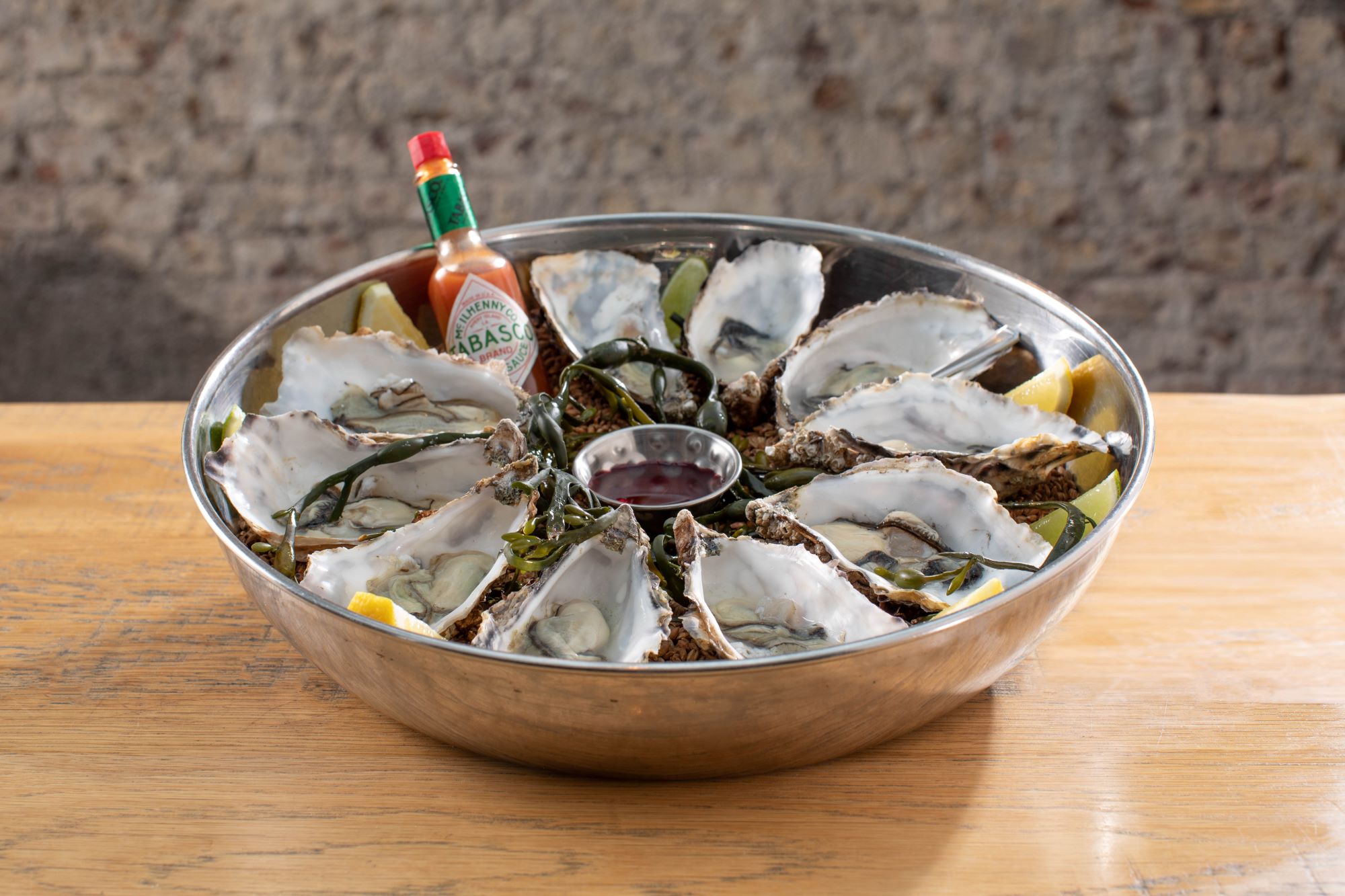 Oysters served in an aluminium bowl with a side of tabasco sauce