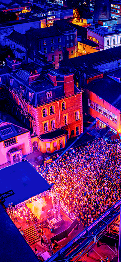 Aerial view of a concert on the St James Gate site of Guinness, people in a crowd surrounded by buildings
