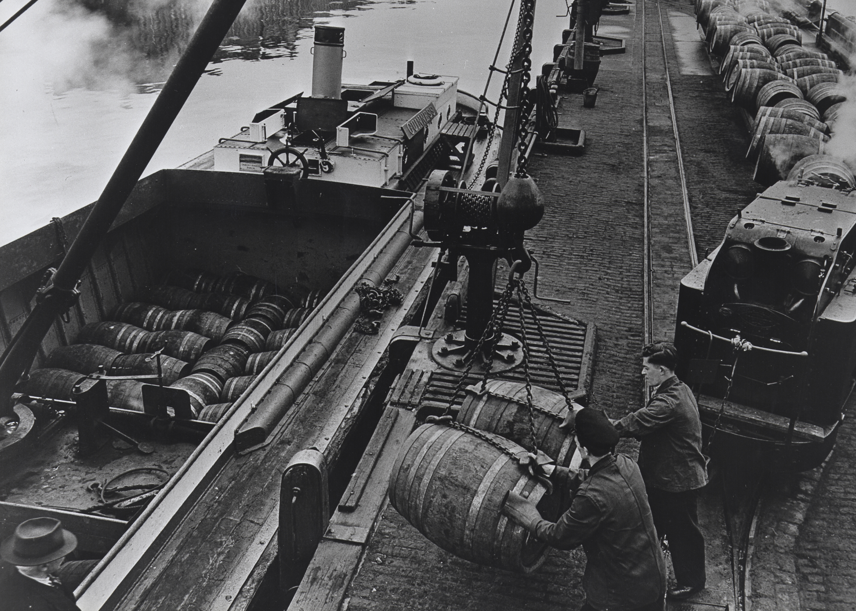 Photograph of barge being loaded with casks at Victoria Quay jetty from a Geoghegan engine, 1955.