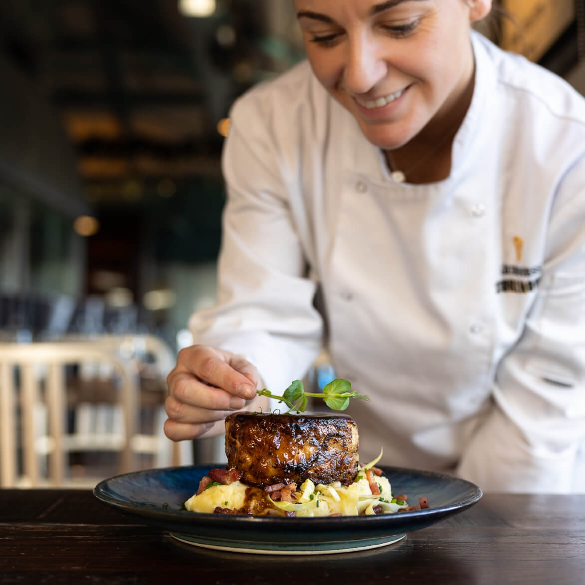 Chef adding the finishing touches to our slow braised crispy Irish pork belly served on creamy mash potato, sauteed cabbage, and bacon.