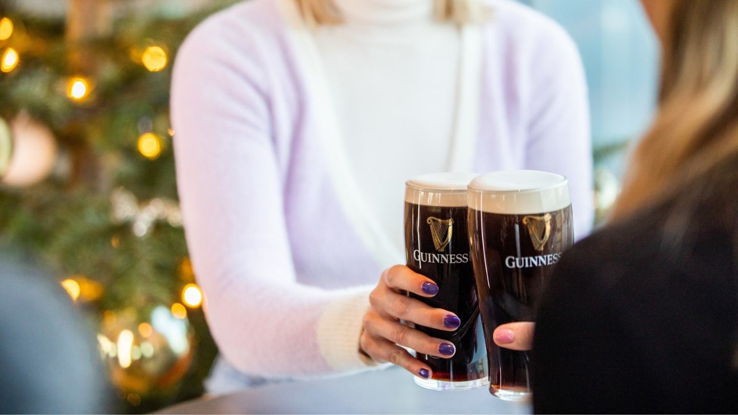 Two women and one man sit in a classic Irish snug, drinking pints of Guinness and water by a Christmas tree. 