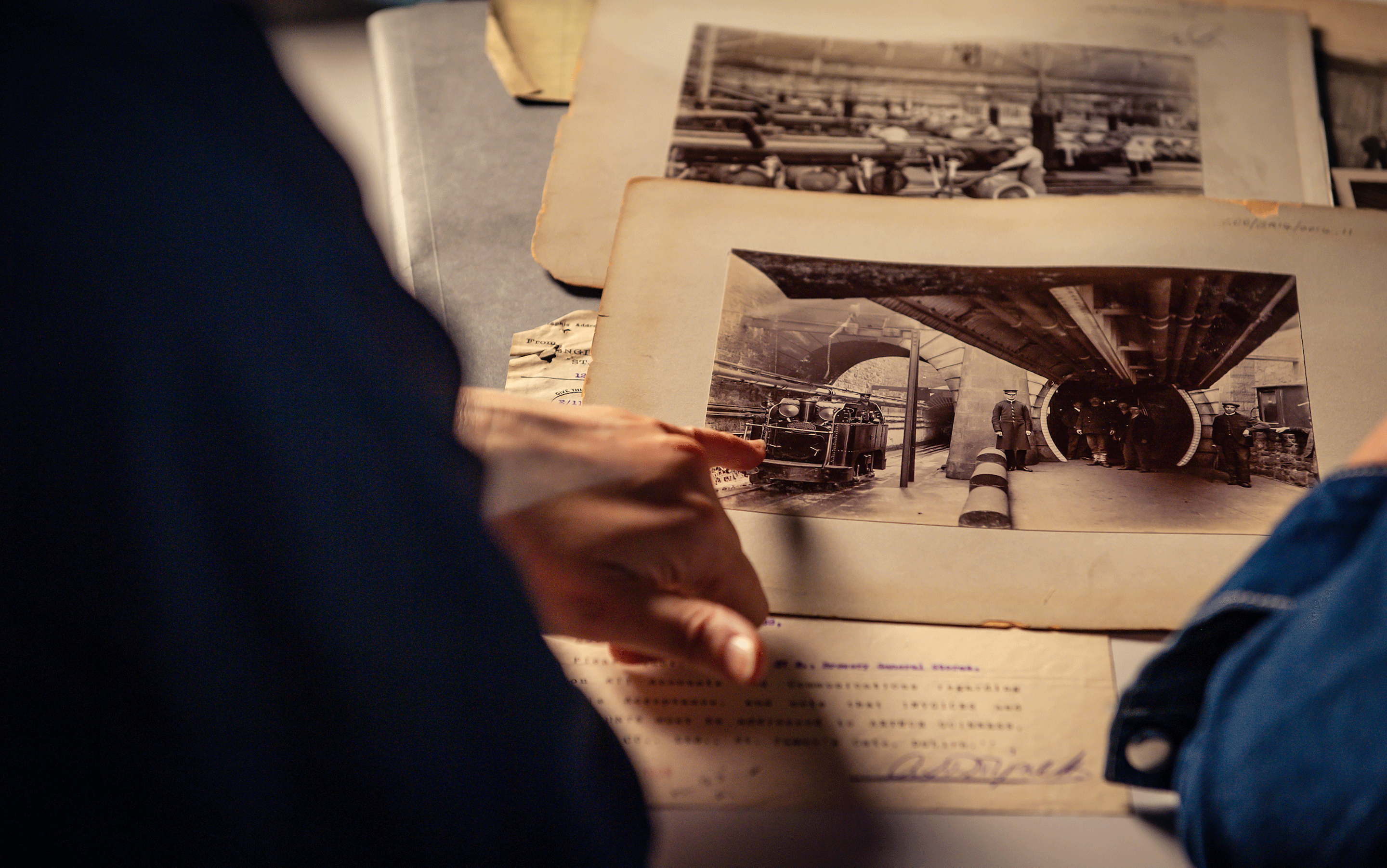 A person pointing at an old black and while image of a tunnel to another person