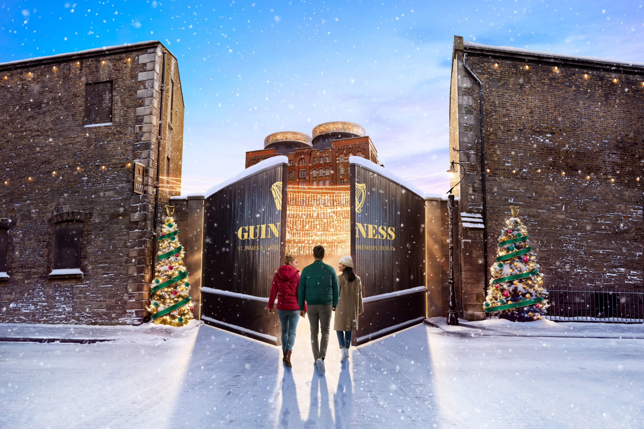A group of three people entering the Guinness Storehouse's main gate with a sight of the building decorated in Christmas decoration