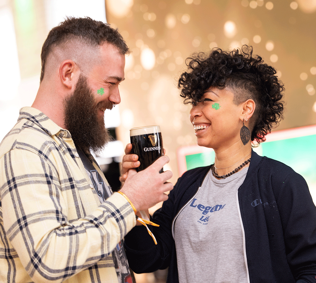 Couple holding a pint of Guinness while looking and smiling to each other