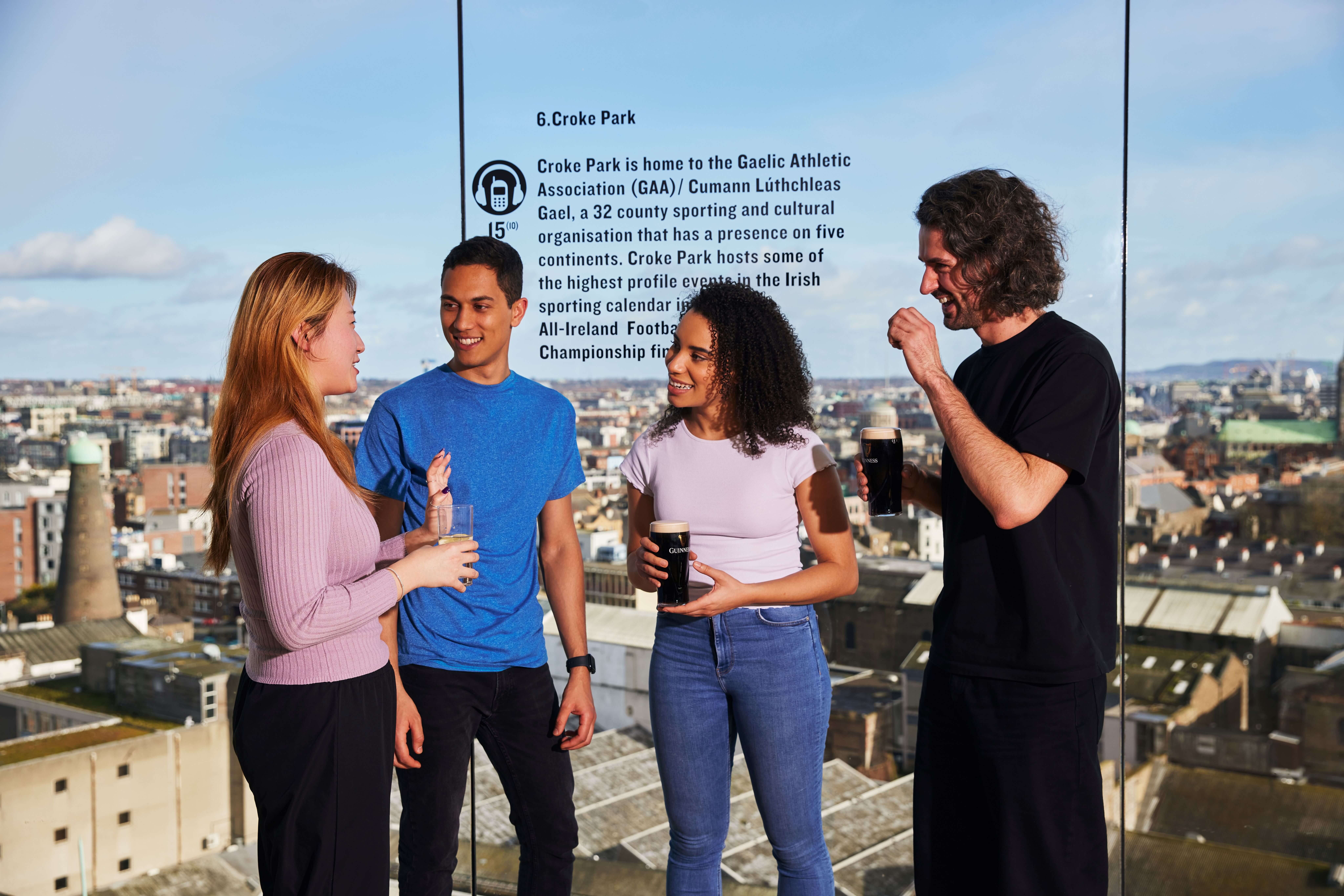 Four friends happily talking and enjoying pints of Guinness at the Gravity Bar