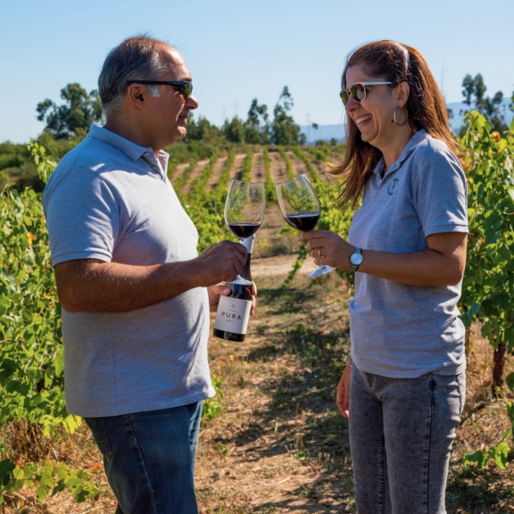 two people in a vineyard drinking red wine