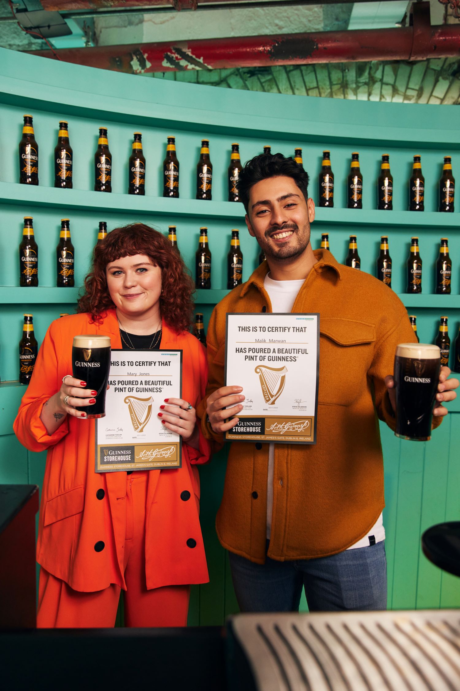 Happy visitors proudly showing their Guinness Academy certificate and beautifully poured pint of Guinness