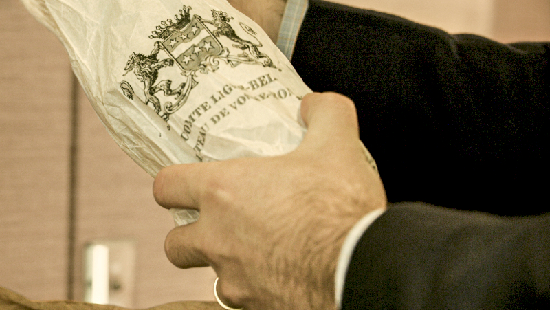 Man holding wine bottle covered in paper packaging