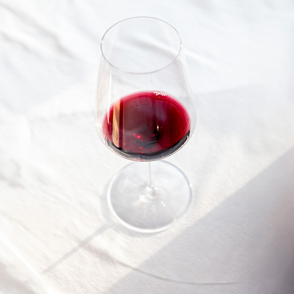 A glass of red wine in a table with a with cloth