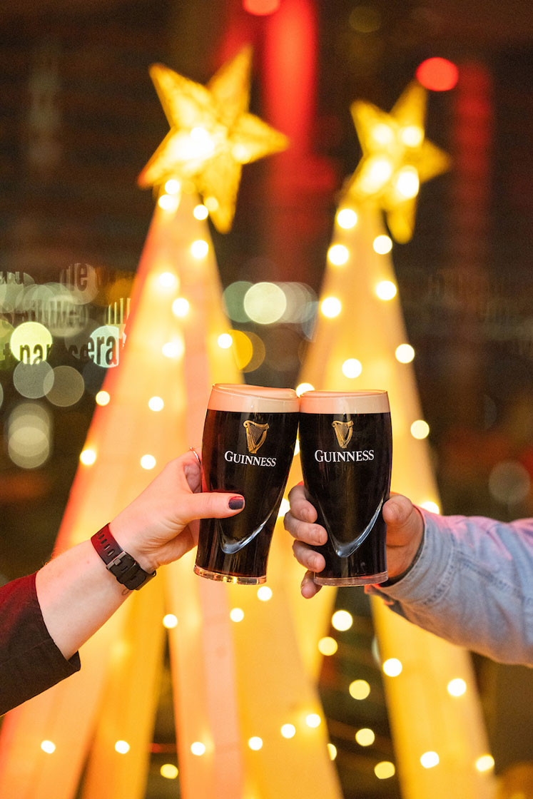 Two pints of Guinness in front of two wooden glittery Christmas tree