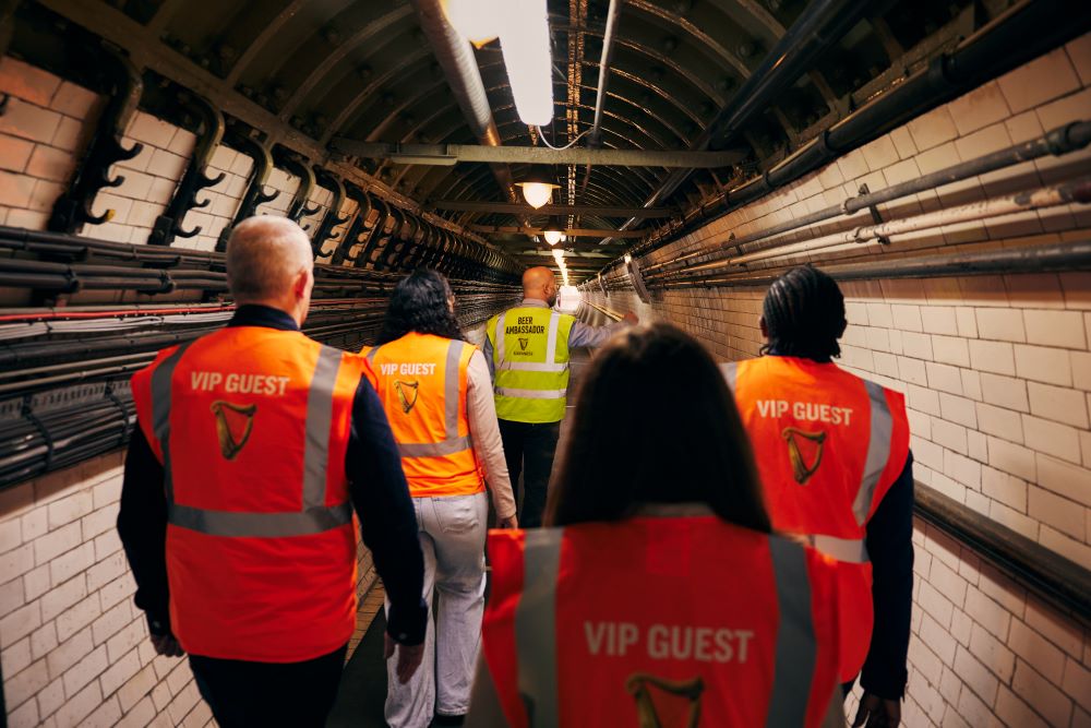 Four visitors following tour guide while visiting the famous Guinness brewery tunnels