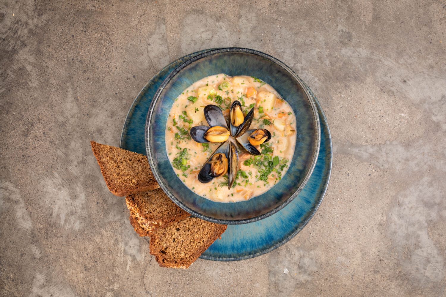 Delicious seafood chowder served on a beautiful blue bowl with a side of brown bread